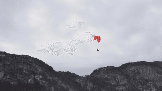 Paraglider soaring over snowy mountains