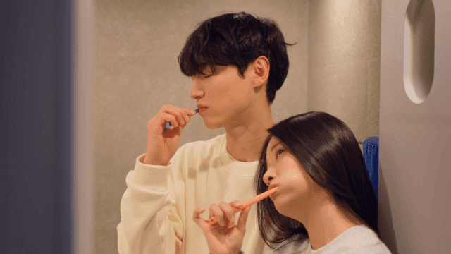 Couple brushing teeth together leaning on each other