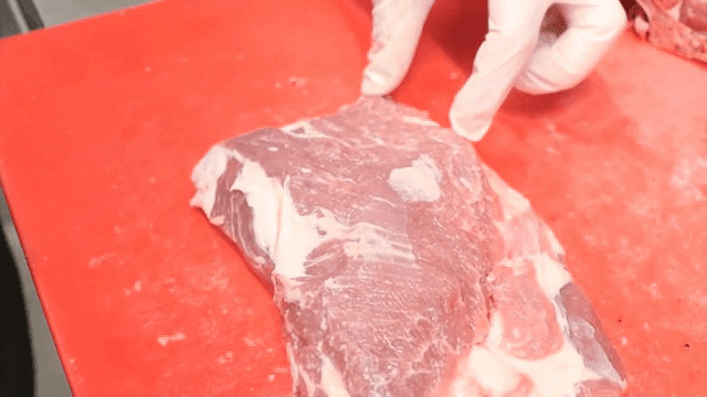 빨간 도마 위에서 고기를 자르는 사람