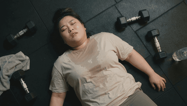 Tired overweight woman lying on gym floor