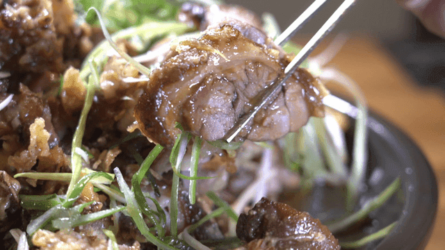 Fried pork trotters picked up with green onions and chopsticks