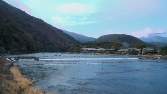 Riverside village with green mountains under a blue sky