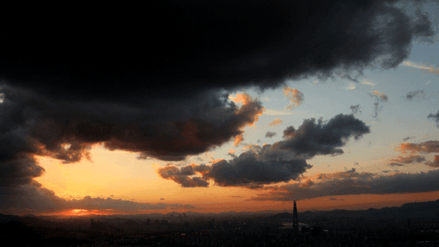 Sunset over a city skyline with clouds