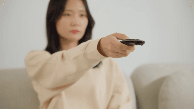 소파에서 리모컨을 조작하는 여자