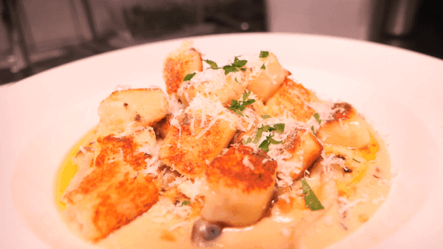 A plate of gnocchi with cheese and herbs