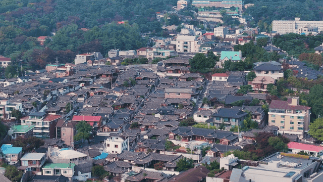 Village with a dense cluster of Hanok houses at the bottom of a hill
