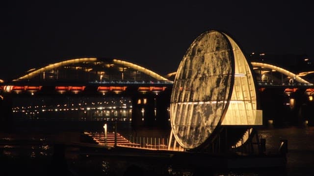 Artificial moon shaped like the moon against the backdrop of a bridge lit up