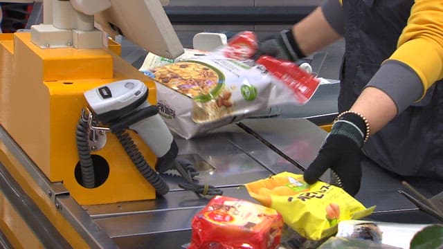 마트의 계산대에서 상품의 바코드를 찍는 점원