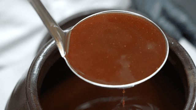 Ladle scooping soy sauce from jar