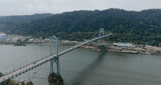 A bridge spanning over a river with forested hills