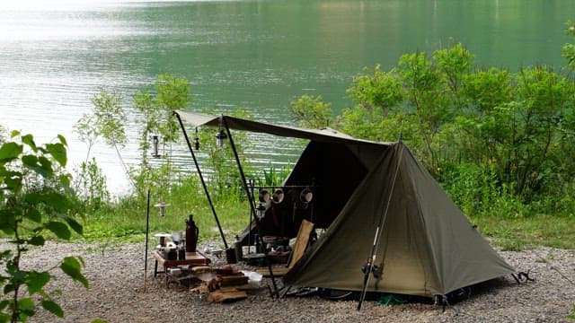 Tent on a quiet lakeside surrounded by lush greenery