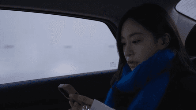 Woman looking at her smartphone in a dark taxi