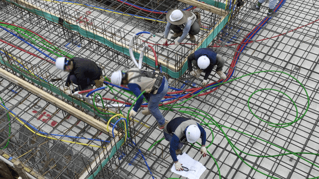 건설 현장 골조 위에서 케이블을 설치하는 작업자들