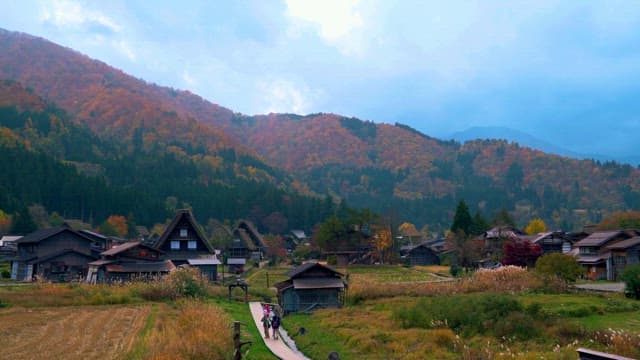 People Walking in Small Village under the Maple Mountain