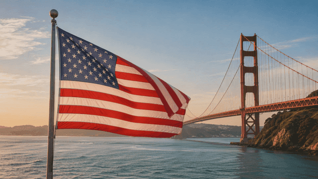 American flag fluttering near suspension bridge