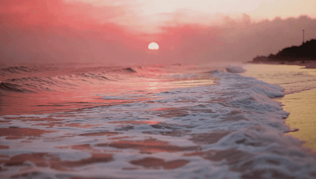Waves gently rolling under a pink sunset