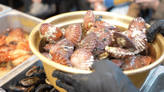 Glovenly hands filling pot with scallops at market
