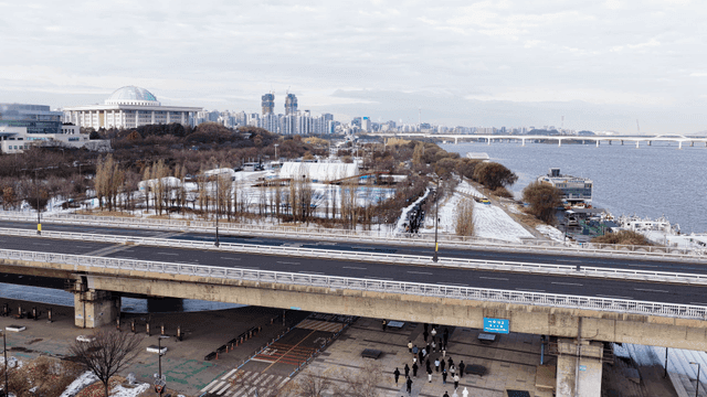Snowy riverside park with city skyline