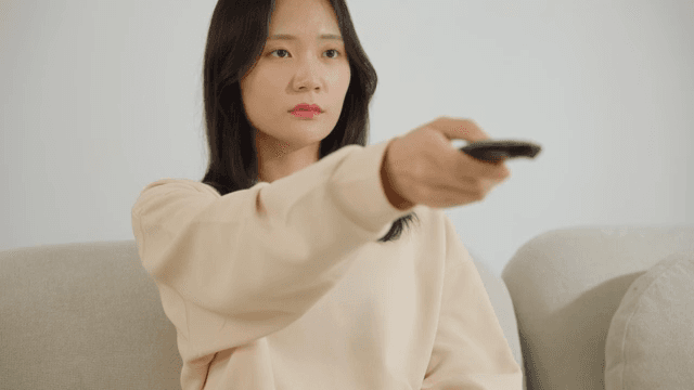 소파에서 리모컨을 조작하는 여자