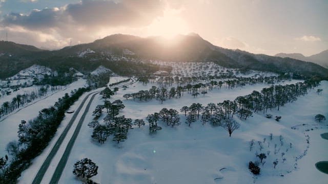 산 너머로 햇빛이 비치는 눈 덮인 풍경