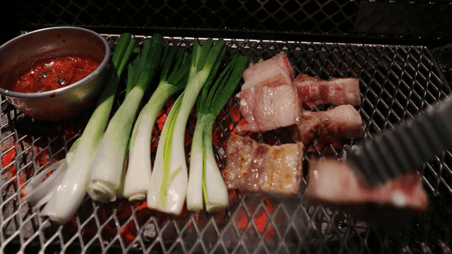Grill plate topped with pork belly and green onions