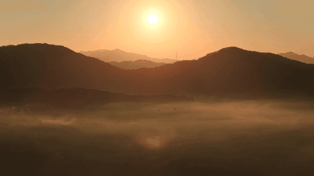 안개 낀 산 위로 떠오르는 해