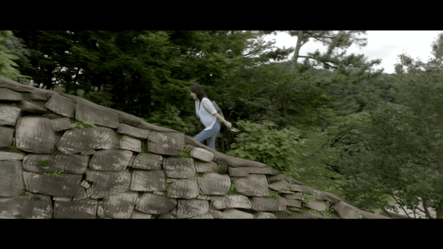 Woman climbing stone wall in forest