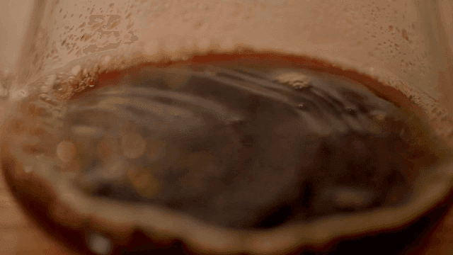 Coffee dripping from glass cup one drop at time