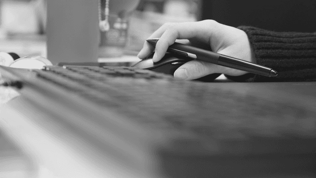 Hand holding a pen on a computer mouse