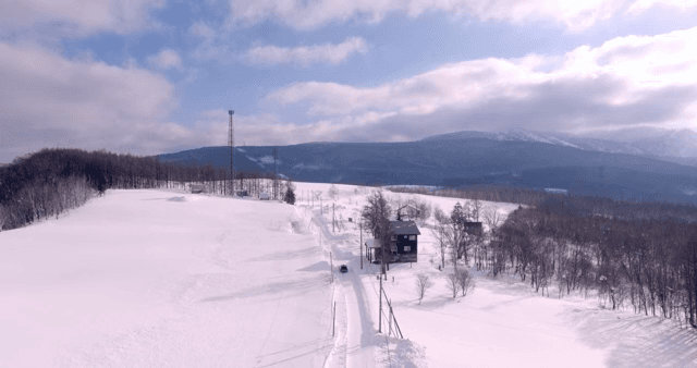 멀리 오두막이 보이는 눈 덮인 도로