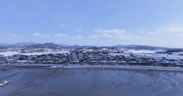 Snow-covered traditional Hanok village by sea