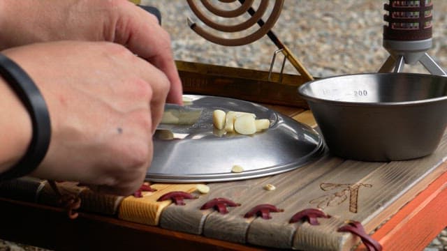 Chopping garlic with a small knife on a wooden table