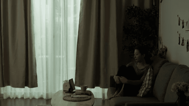 어두운 방에서 소파에 앉아 있는 여성