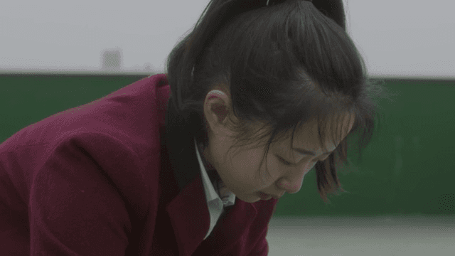 아래를 보고 있는 버건디색 교복을 입은 학생