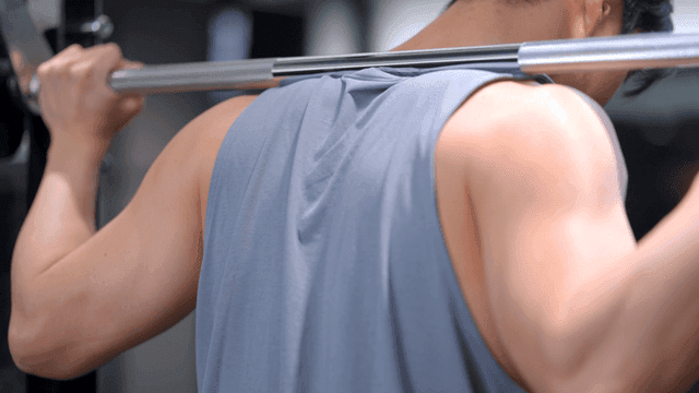 헬스장에서 어깨에 무게를 지고 스쿼트를 하는 남자