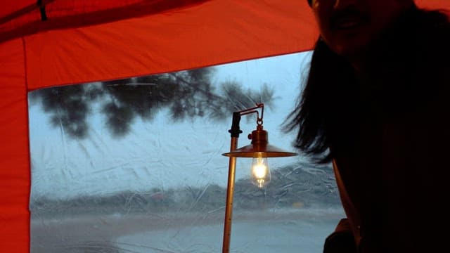 텐트 밖 고요한 풍경을 배경으로 빛나는 램프