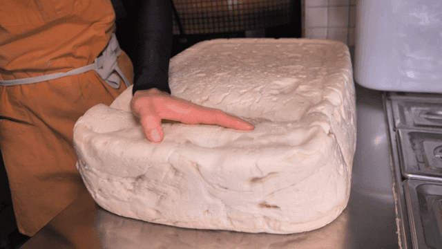 Cutting a large block of dough in a kitchen