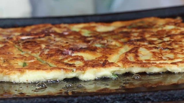Crispy Korean pancake being cooked on a hot pan
