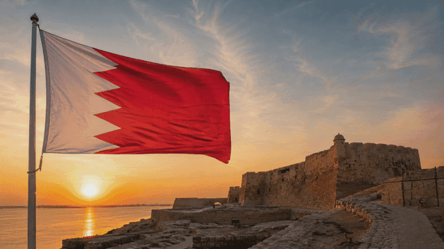 Bahraini flag fluttering near ancient fortress at sunset