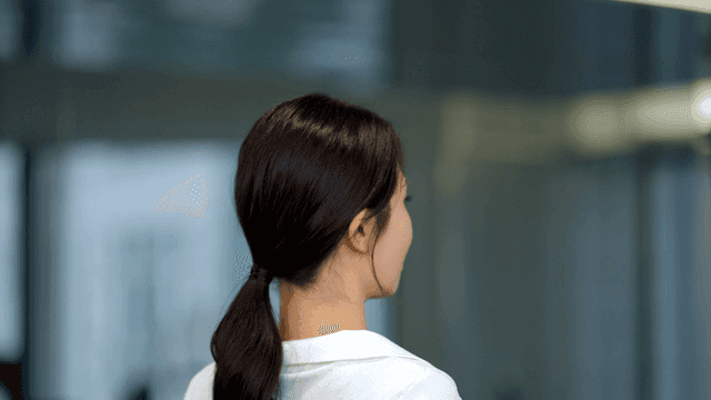 묶은 머리를 정리하고 뒤를 보며 미소짓는 젊은 여성