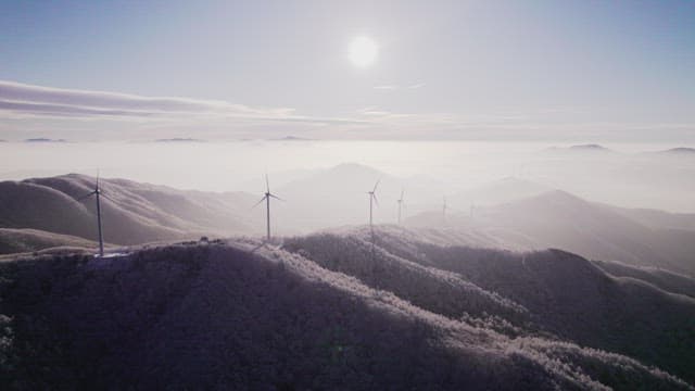 Wind Generators on Misty and Snowy Mountain in the Morning