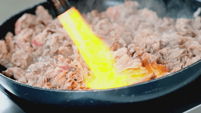 팬에서 토치로 고기를 굽는 장면