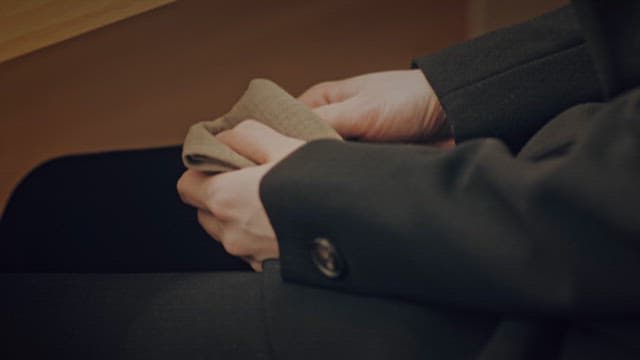 Person Clasping Hands Resting on Lap