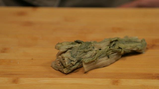 Cutting fermented kimchi on a wooden cutting board