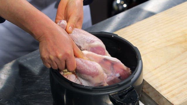 Placing raw chicken into a pot