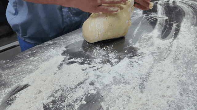 Person kneading dough on a floured table