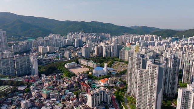 한낮의 산으로 둘러싸인 건물이 밀집된 도시의 풍경