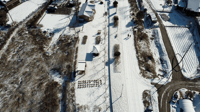 Snow-covered rural path with two people walking