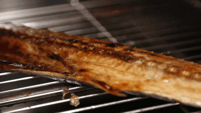 Grilled mackerel being cooked on metal rack