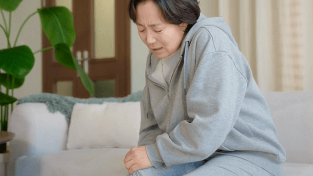 무릎을 잡고 불편해하는 여성